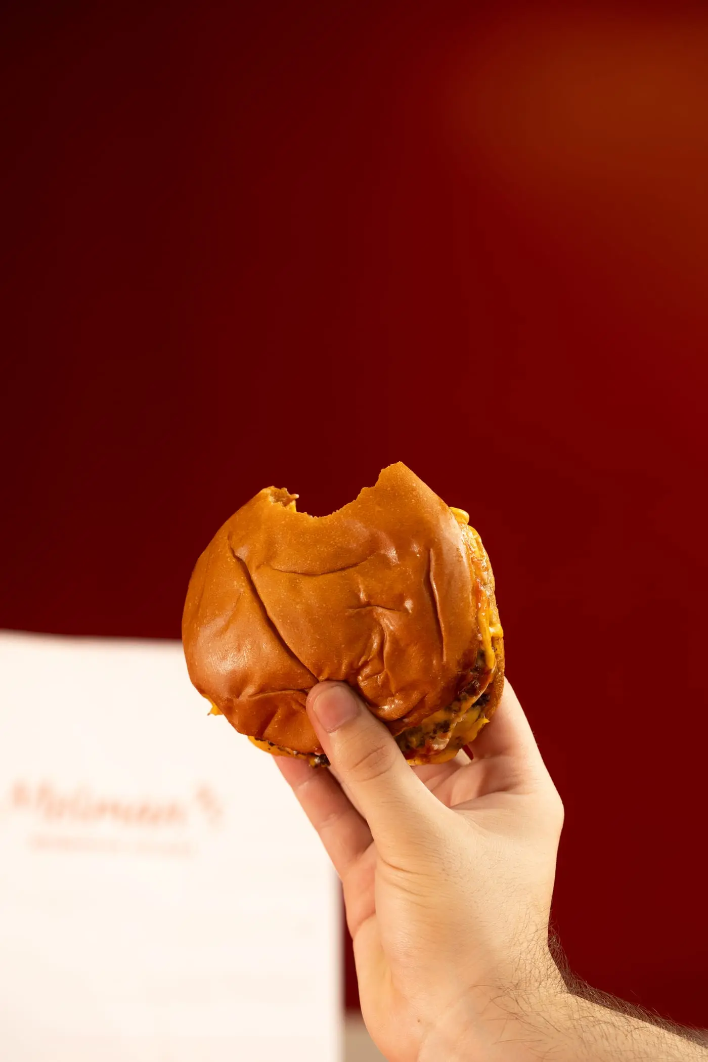 Hamburguesa recién mordida sostenida con una mano