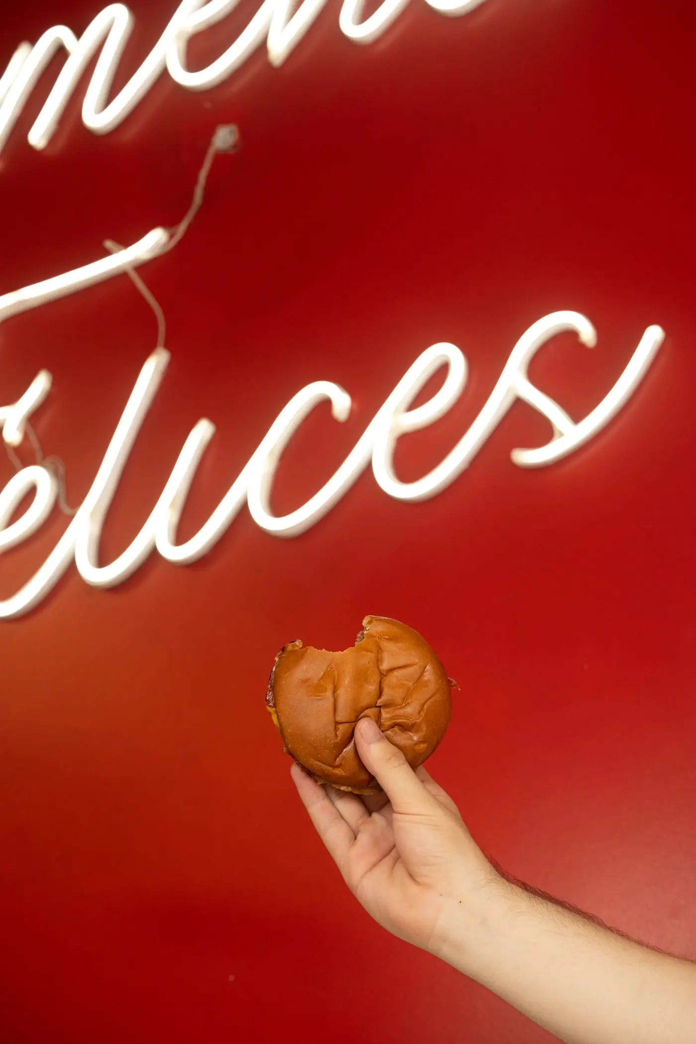 Cartel de neón de Melman’s con la frase “momentos felices” y una hamburguesa mordida